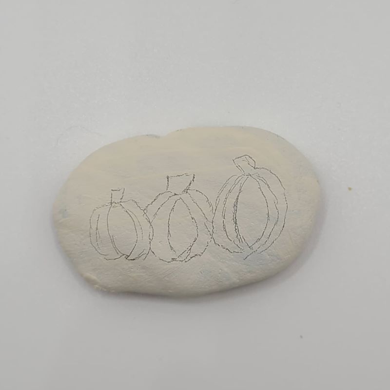Drawing pumpkins on a rock